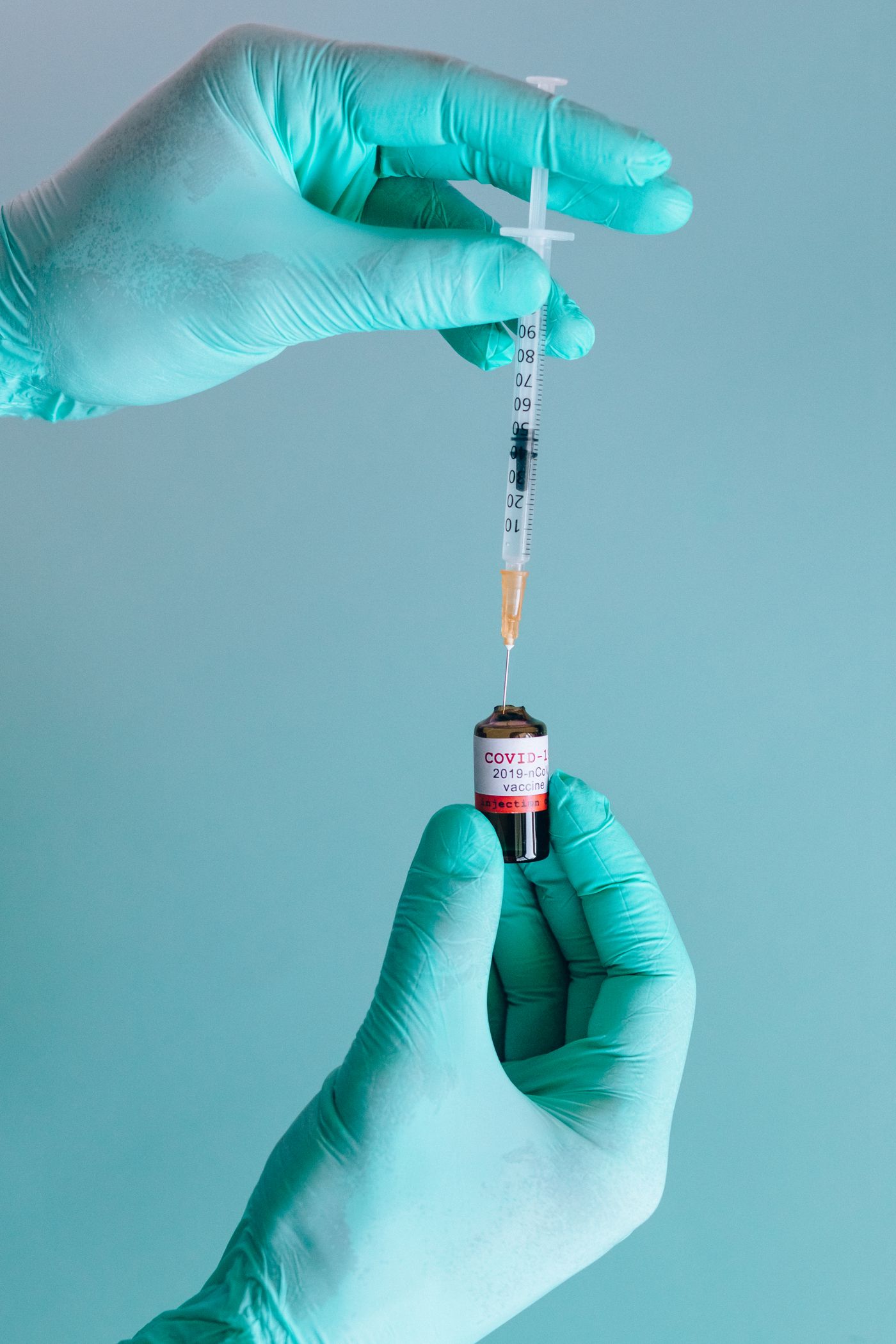 Préparation d'un vaccin : seringue et flacon tenus par des gants médicaux